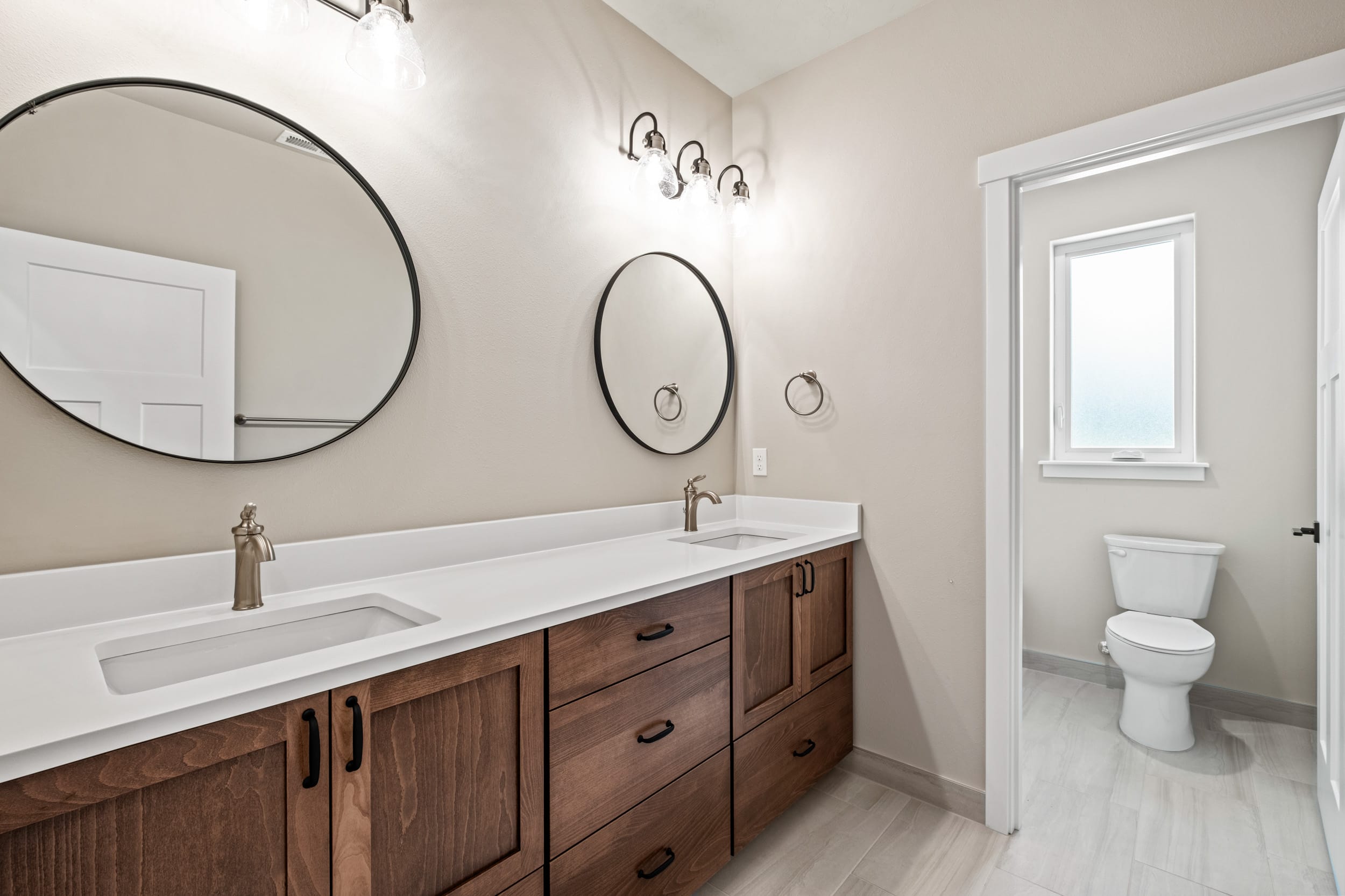 Modern bathroom with double sinks and round mirrors.