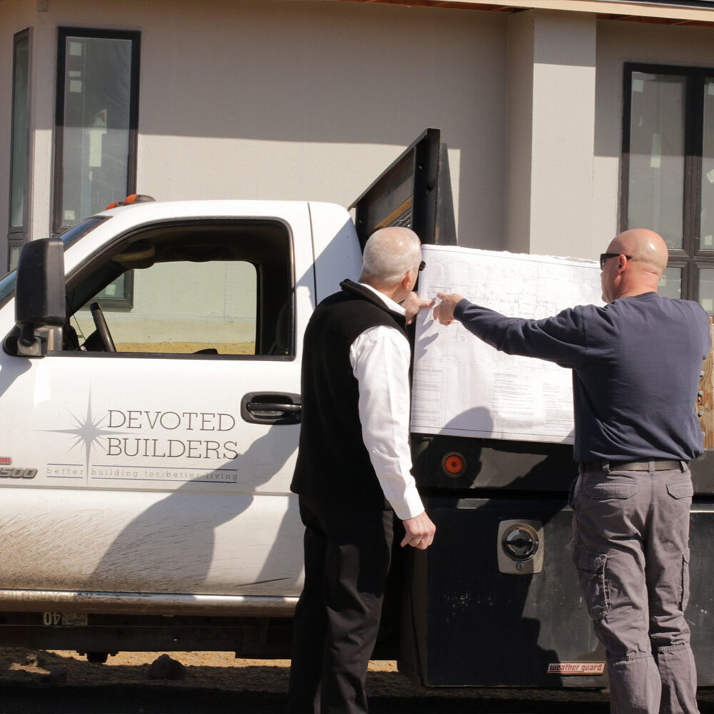 Builders reviewing plans by construction truck.